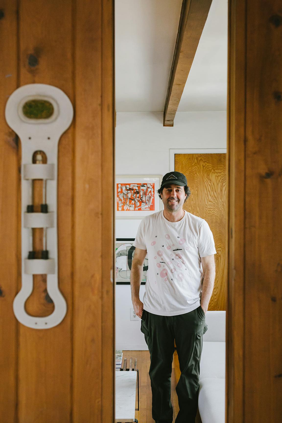 A masculine person stands and smiles, seen through a narrow doorway.